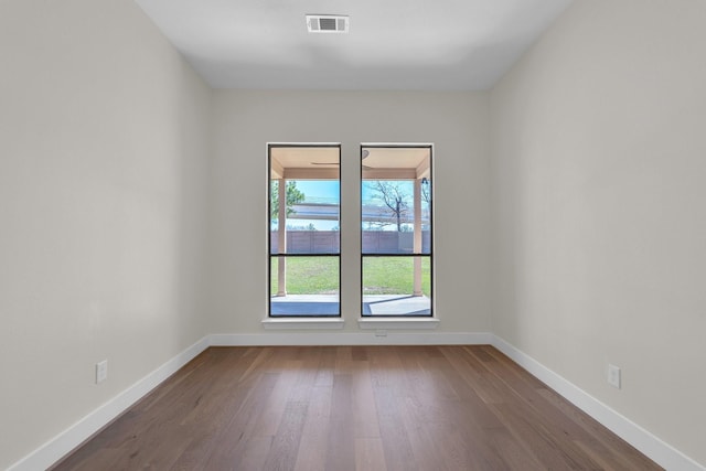 unfurnished room featuring baseboards, visible vents, and dark wood-type flooring