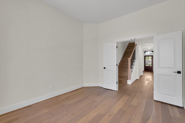 unfurnished room with stairway, baseboards, and wood finished floors