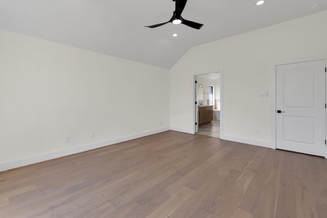 unfurnished bedroom with connected bathroom, recessed lighting, wood finished floors, baseboards, and vaulted ceiling