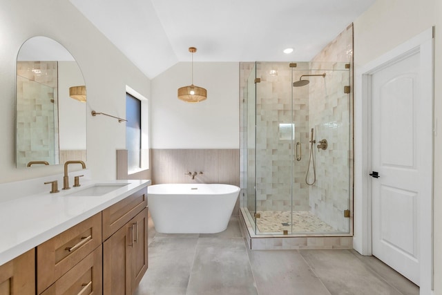 bathroom with lofted ceiling, a freestanding bath, wainscoting, a shower stall, and vanity