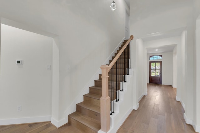 staircase featuring wood finished floors and baseboards