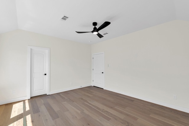 unfurnished room with lofted ceiling, visible vents, ceiling fan, wood finished floors, and baseboards