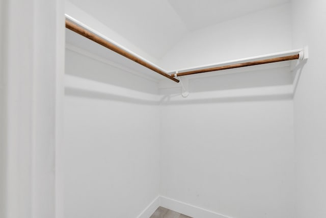 spacious closet with lofted ceiling and wood finished floors