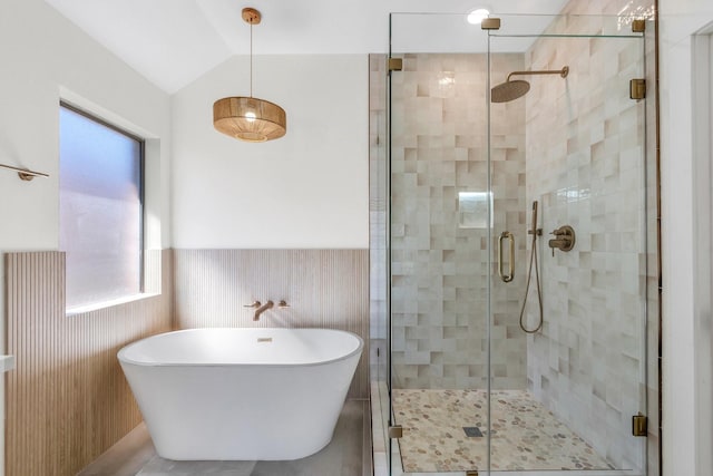 full bath featuring lofted ceiling, wainscoting, a freestanding bath, and a shower stall