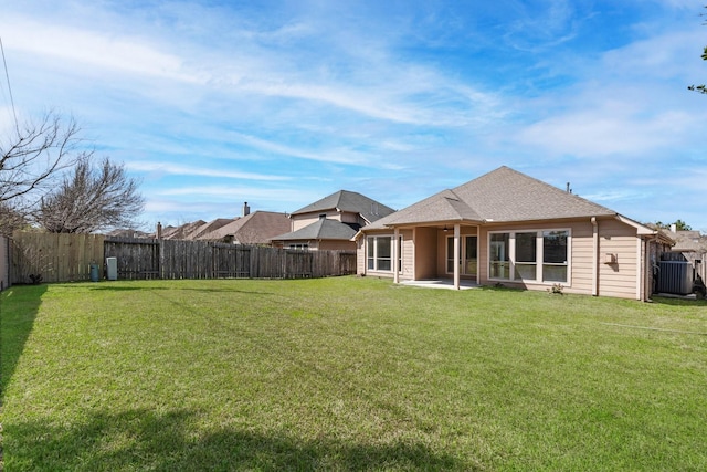 back of property with a shingled roof, a fenced backyard, a yard, and a patio