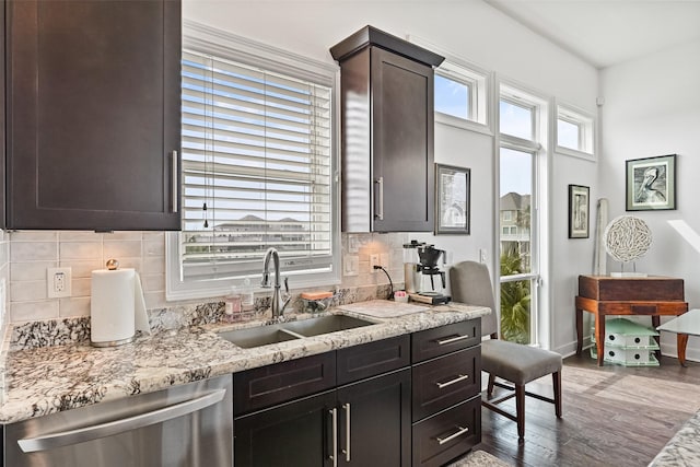 kitchen featuring wood finished floors, baseboards, a sink, dishwasher, and backsplash