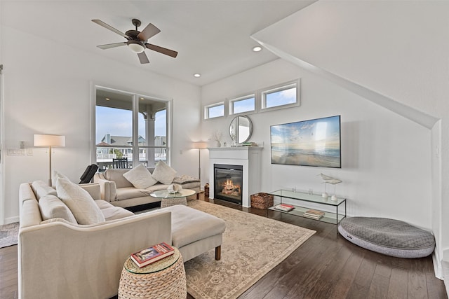 living room featuring dark wood finished floors, a glass covered fireplace, recessed lighting, and ceiling fan