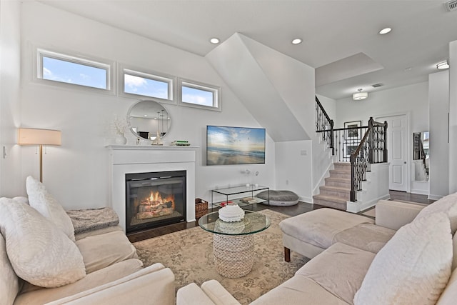 living area featuring baseboards, stairs, recessed lighting, wood finished floors, and a glass covered fireplace
