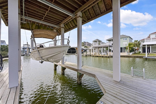 view of dock with a residential view, a water view, and boat lift