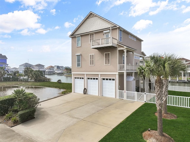 view of front of property with a water view, driveway, fence, a garage, and a balcony