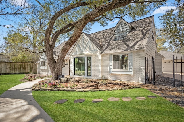 tudor house featuring a front lawn, fence, and brick siding