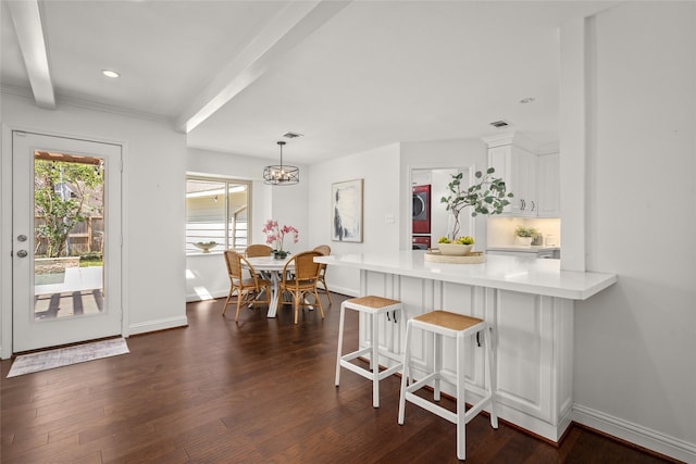 kitchen featuring baseboards, a peninsula, dark wood-style flooring, light countertops, and white cabinets