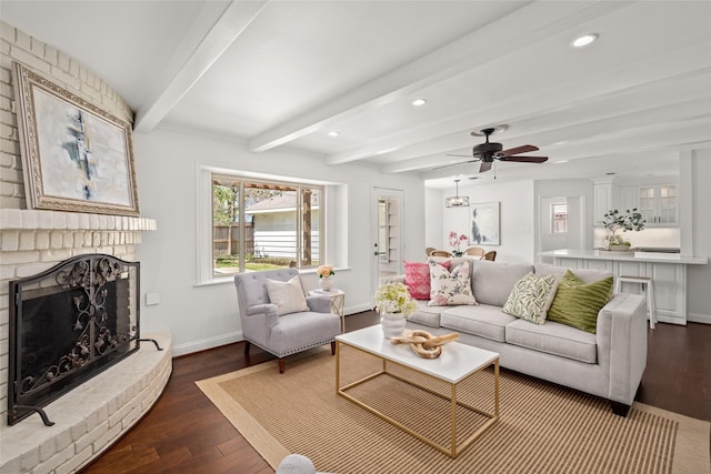 living room featuring dark wood-type flooring, a brick fireplace, baseboards, and beam ceiling