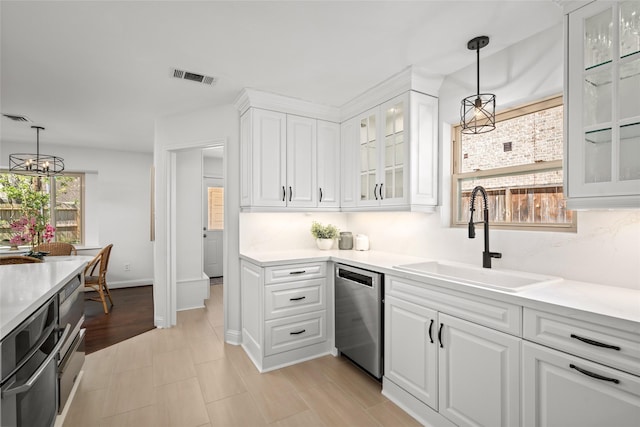 kitchen featuring visible vents, backsplash, stainless steel dishwasher, white cabinetry, and a sink