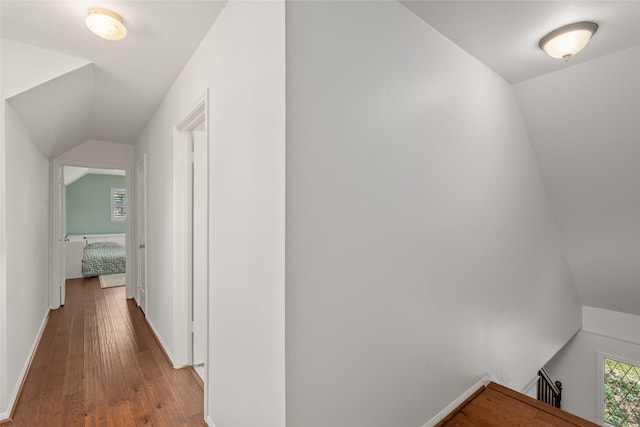 corridor featuring vaulted ceiling, wood finished floors, and baseboards