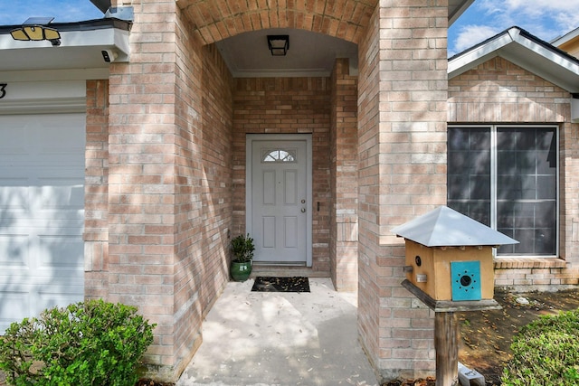 property entrance with an attached garage and brick siding