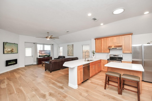 kitchen with visible vents, appliances with stainless steel finishes, a peninsula, light brown cabinetry, and under cabinet range hood