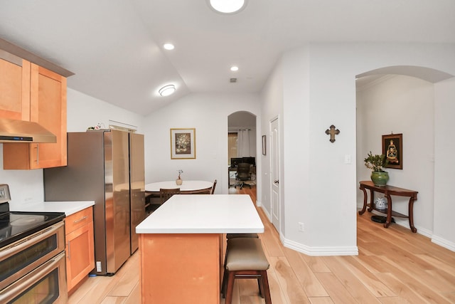 kitchen with arched walkways, a breakfast bar area, light wood-style flooring, stainless steel appliances, and a center island