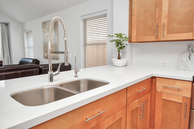 kitchen featuring brown cabinets, open floor plan, light countertops, and a sink