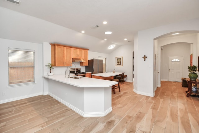 kitchen with arched walkways, stainless steel appliances, visible vents, vaulted ceiling, and light countertops