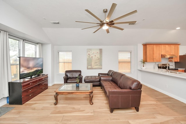 living area with vaulted ceiling, light wood-type flooring, a ceiling fan, and baseboards