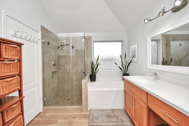 bathroom featuring lofted ceiling, a shower stall, a bath, and vanity