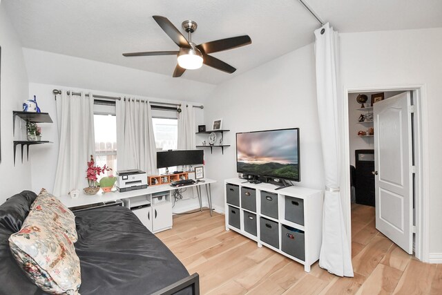 living room with lofted ceiling, light wood-style flooring, and a ceiling fan