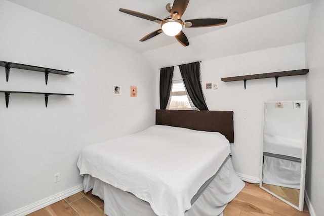 bedroom with ceiling fan, vaulted ceiling, baseboards, and wood finished floors