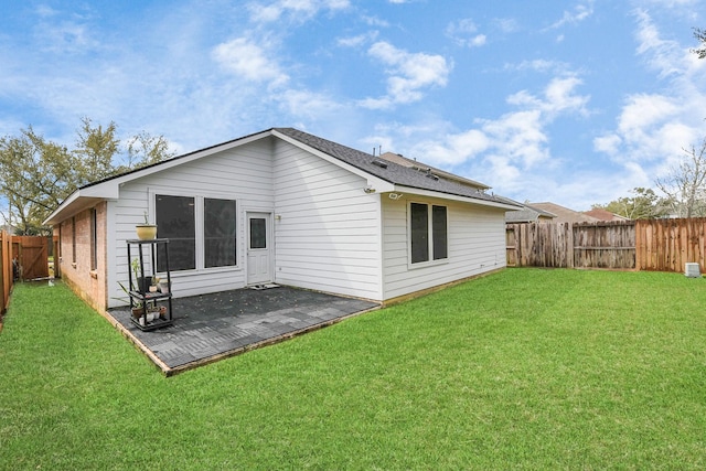 rear view of property featuring a fenced backyard and a lawn