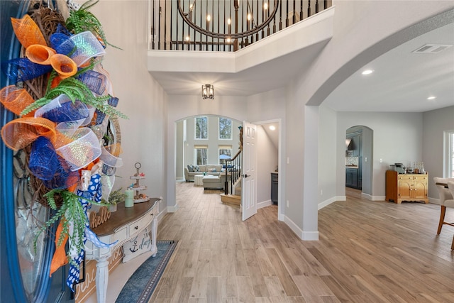 entryway with a wealth of natural light, arched walkways, stairway, and wood finished floors