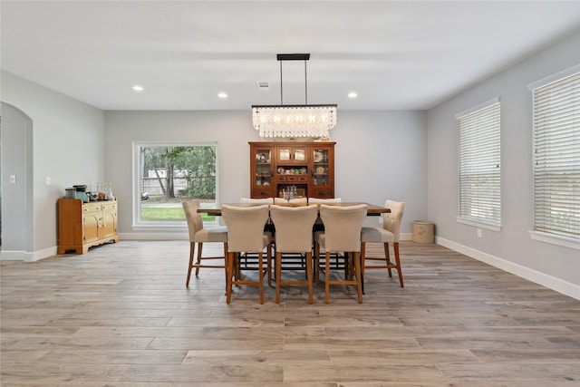 dining room featuring arched walkways, light wood-type flooring, baseboards, and recessed lighting