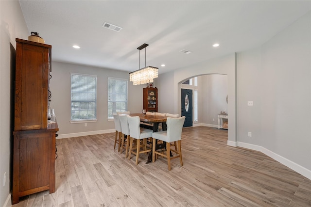 dining area featuring light wood finished floors, visible vents, arched walkways, and recessed lighting