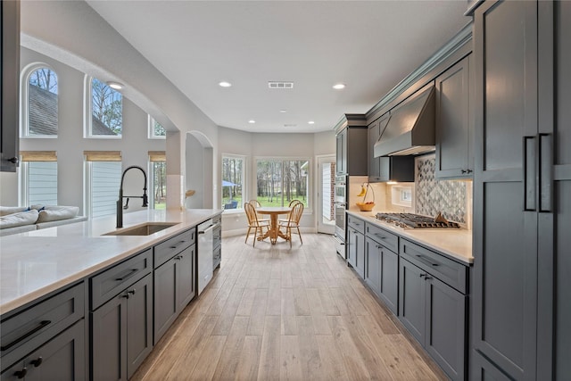 kitchen featuring stainless steel appliances, visible vents, decorative backsplash, a sink, and extractor fan