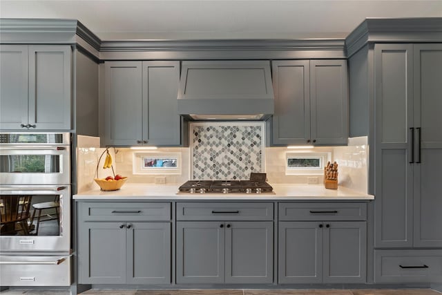 kitchen featuring light countertops, stainless steel appliances, gray cabinetry, premium range hood, and a warming drawer