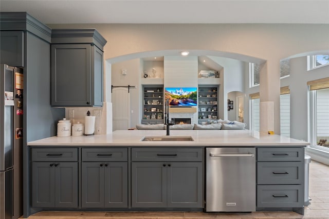 kitchen featuring a sink, light countertops, gray cabinets, and stainless steel refrigerator