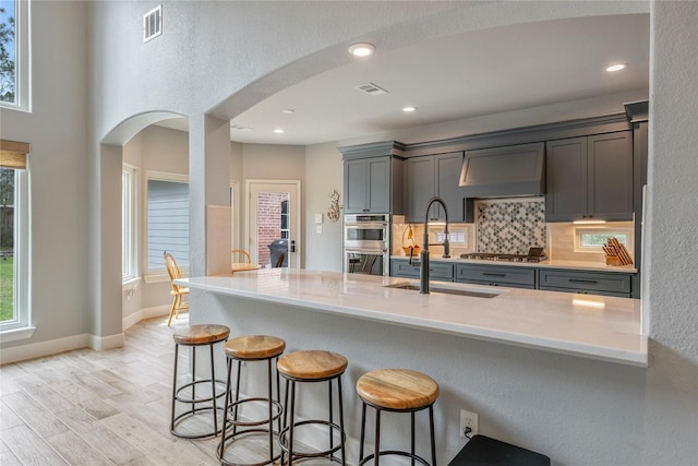 kitchen featuring tasteful backsplash, visible vents, arched walkways, light wood-style flooring, and stainless steel appliances