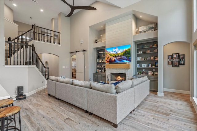 living area featuring arched walkways, a barn door, light wood-type flooring, and a ceiling fan