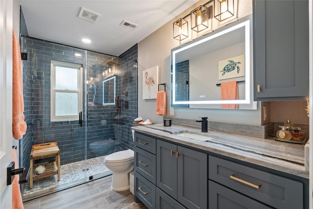 bathroom featuring toilet, a shower stall, visible vents, and vanity