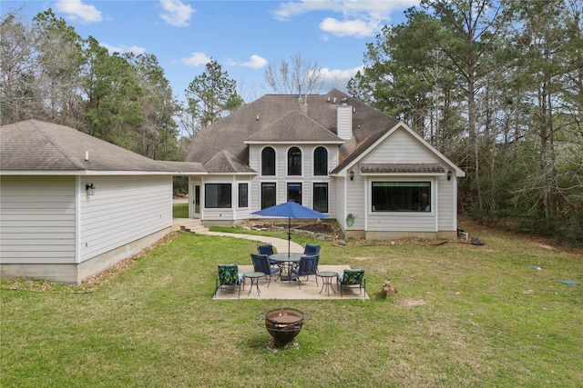 back of property featuring a fire pit, a yard, roof with shingles, a chimney, and a patio area