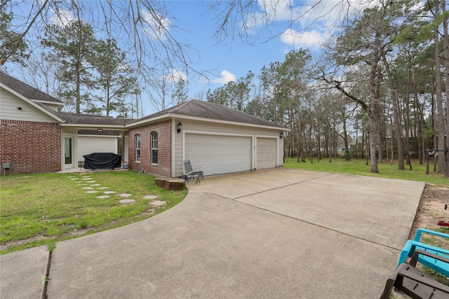 view of property exterior with a garage, brick siding, driveway, and a yard