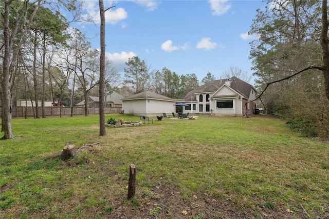 rear view of house featuring fence and a lawn