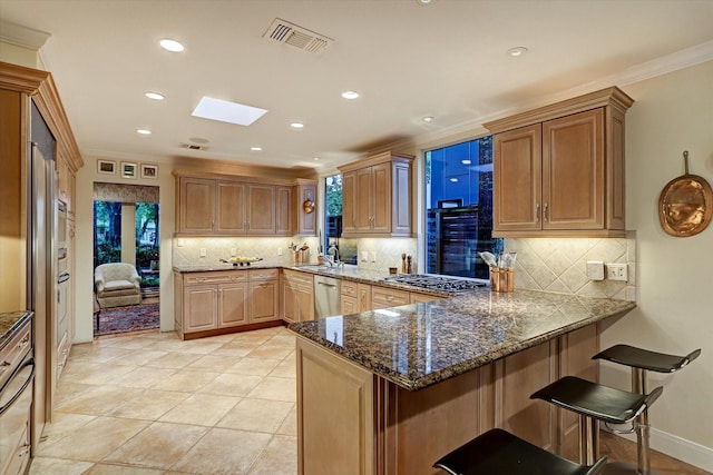 kitchen featuring a skylight, visible vents, appliances with stainless steel finishes, a sink, and a peninsula