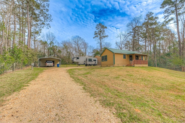 view of front of house with dirt driveway, a detached carport, metal roof, fence, and a front lawn