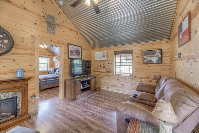 living area featuring a healthy amount of sunlight, a tiled fireplace, wood finished floors, and lofted ceiling