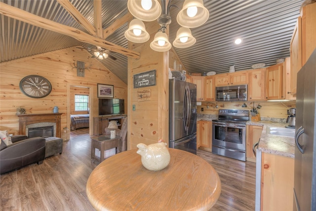 dining room with vaulted ceiling with beams, a glass covered fireplace, wood walls, and wood finished floors