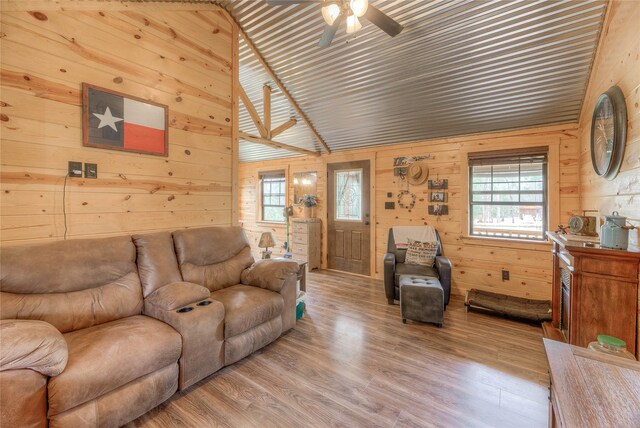 living area with ceiling fan, wood walls, and wood finished floors