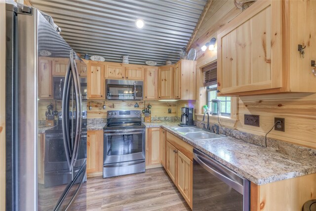 kitchen featuring a sink, light countertops, appliances with stainless steel finishes, light wood-type flooring, and light brown cabinetry