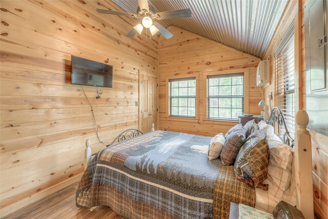 bedroom featuring vaulted ceiling, wood walls, wood finished floors, and a ceiling fan