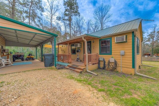 view of outbuilding with dirt driveway, a carport, and fence