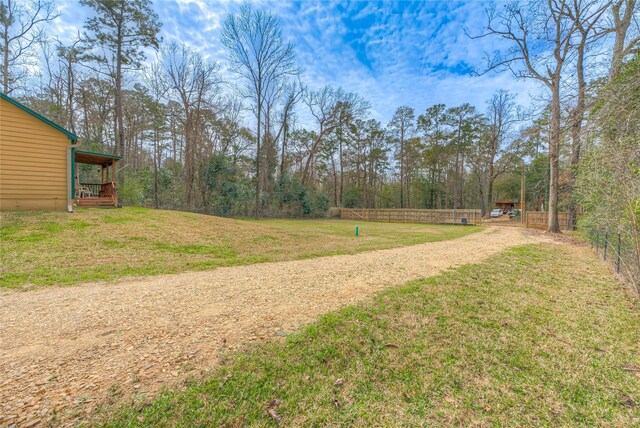 view of yard featuring dirt driveway and fence